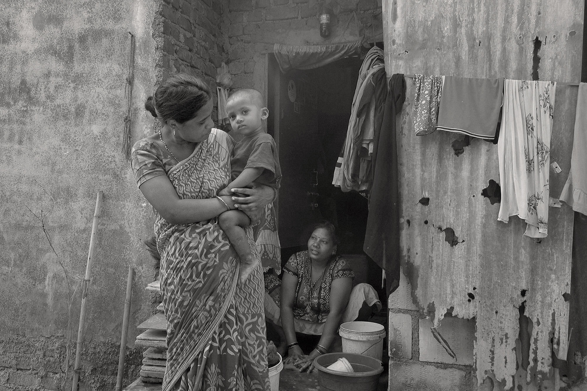 Christoph Radke, India, Mumbai, eine junge Mutter mit Kind auf dem Arm in einem Slum, 2020